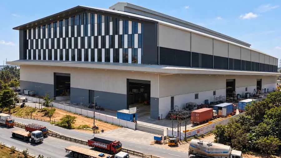 Modern industrial warehouse with a louvred glass facade beside a truck yard